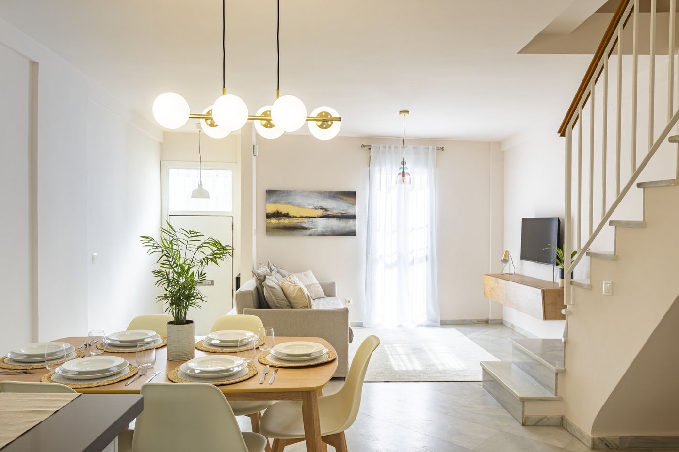 Comedor luminoso Casa Postrera con lámpara dorada