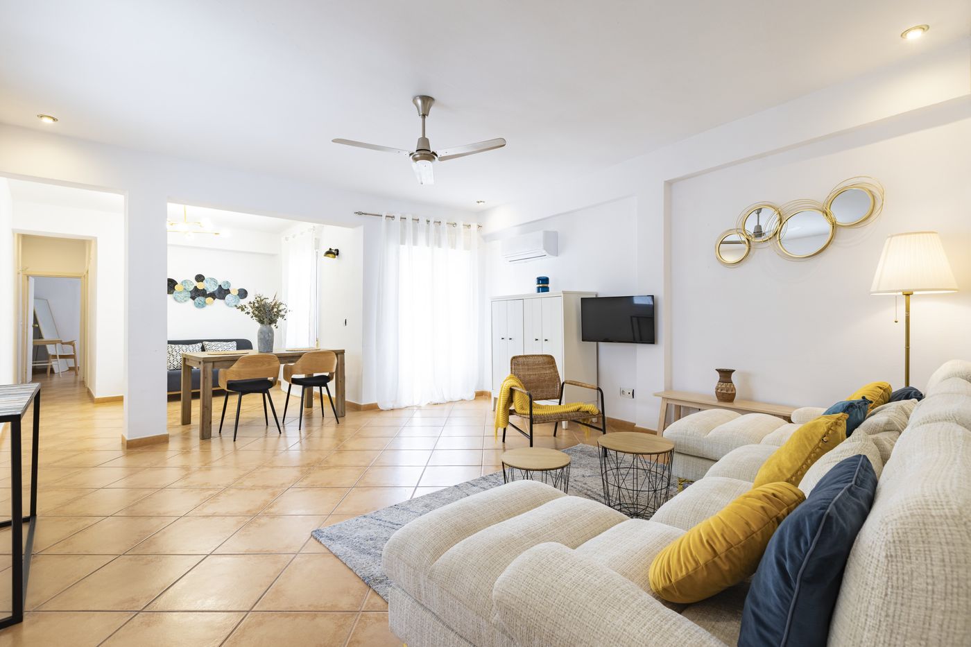 Salón amplio con sofá tostado y sillón de mimbre